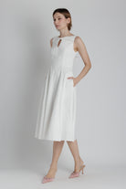 Woman wearing a white sleeveless dress on a plain background