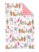 A white fabric towel, featuring a colorful cartoon pattern of Christmas characters around a manger. The top right corner is folded over to show the reverse side, which has a pink and orange striped pattern with a gold star.