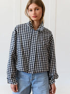 Person wearing a black and white checkered shirt with blue jeans against a white background