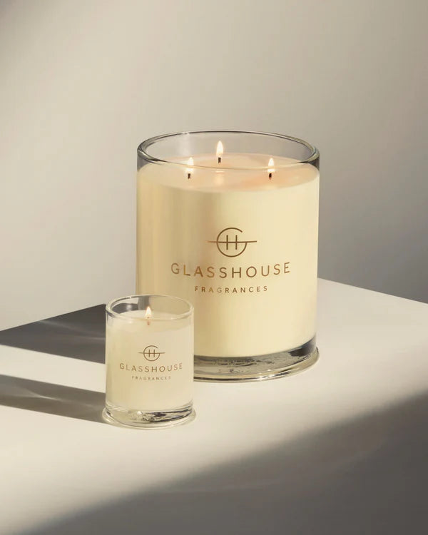 Two glass candles with 'Glasshouse Fragrances' logo on a neutral background