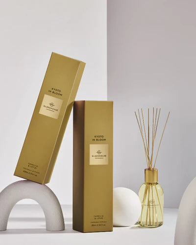 Two gold boxes labeled 'Kinto in Bloom' with a glass diffuser bottle on a light gray background.