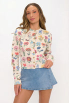 Woman wearing a floral long-sleeve top and denim skirt on a white background