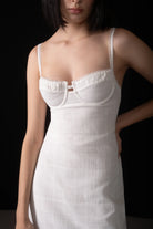 Woman wearing a white dress with thin straps against a black background