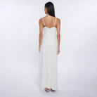 Woman wearing a white dress with thin straps on a plain background