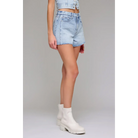 Person wearing light blue denim shorts and white boots on a gray background