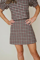 Person wearing a houndstooth pattern dress against a neutral background