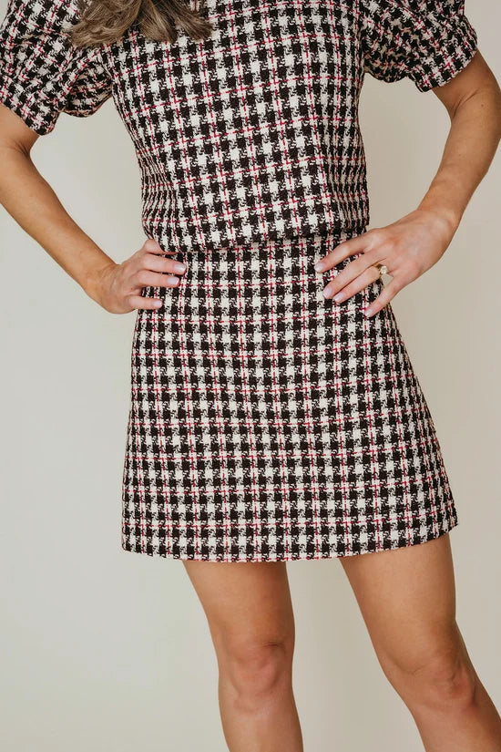Person wearing a houndstooth pattern dress against a neutral background