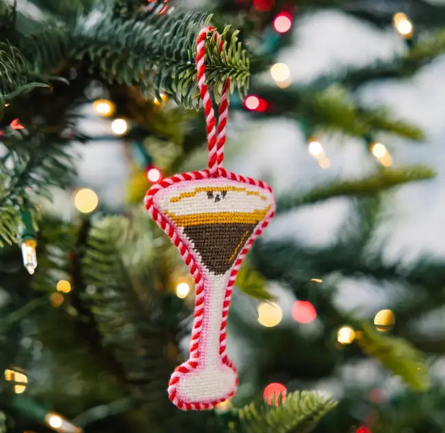 Decorative Christmas ornament shaped like a espresso martini glass on a tree with lights in the background