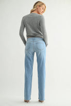 Woman wearing a gray sweater and light blue jeans on a white background