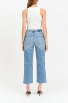 Woman wearing light blue jeans and a white top on a white background