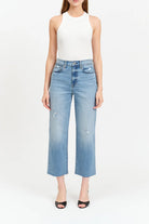 Woman wearing light blue jeans and a white top on a white background