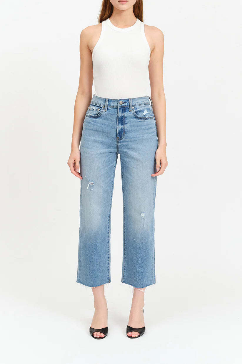 Woman wearing light blue jeans and a white top on a white background