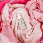 Bottle of 'Sweet Grace' fabric softener on pink towels in a pink basket