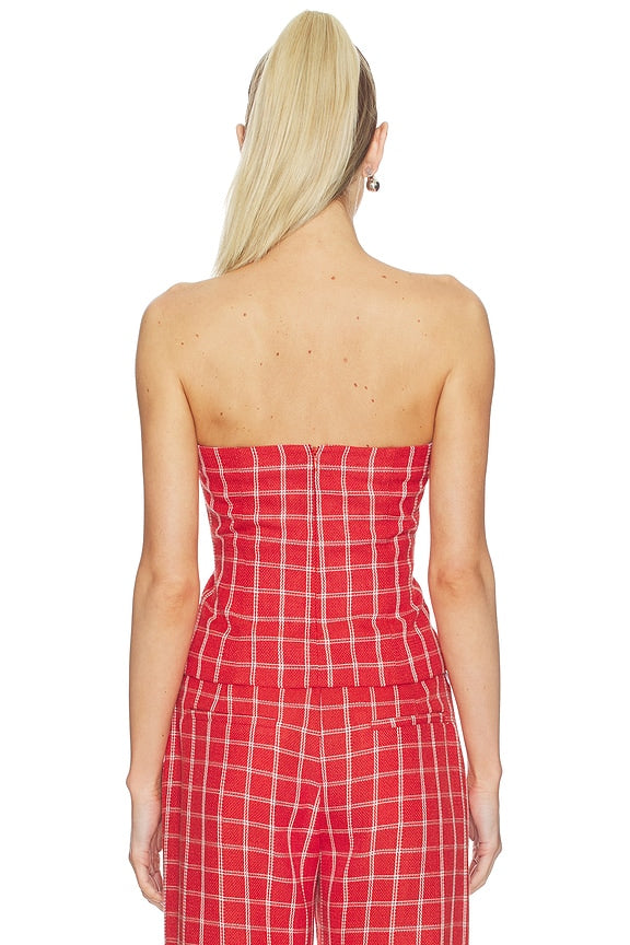Woman wearing a strapless red plaid jumpsuit on a white background