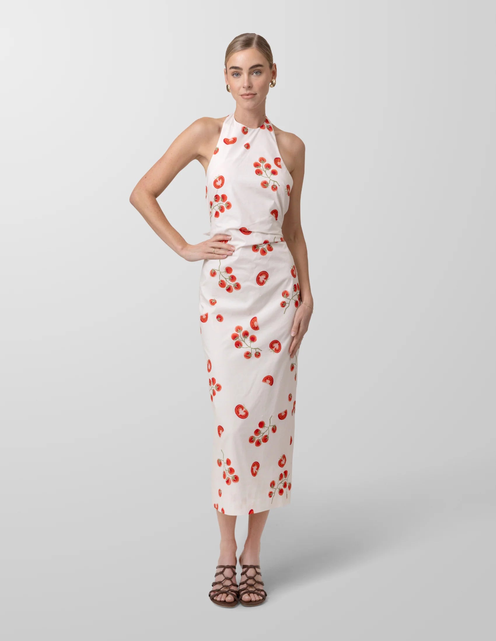 Woman wearing a white dress with red tomato pattern on a gray background