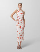 Woman wearing a white dress with red tomato pattern on a gray background