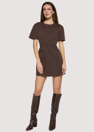 A woman modeling a short-sleeve brown mini dress with a button-front detail and matching brown knee-high boots, set against a solid light gray background.