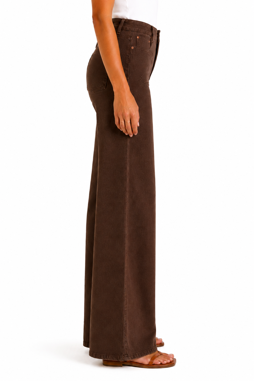 A side profile view of a model wearing dark brown wide-leg jeans and brown flat sandals against a plain white background.