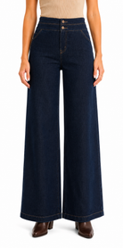 A model wearing dark navy blue wide-leg denim pants with a high waist and double button closure, paired with brown ankle boots against a plain white background.