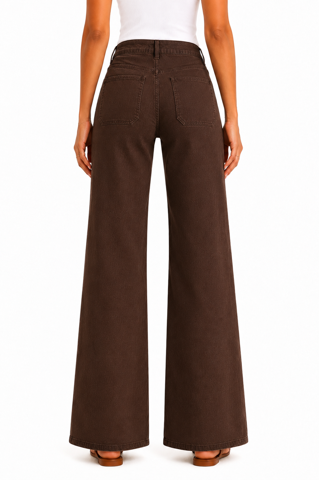 A person shown from the back wearing dark brown wide-leg pants, a white top, and brown sandals against a plain white studio background.